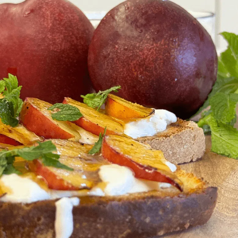 bruschetta con stracciatella e pesche e pesche sullo sfondo