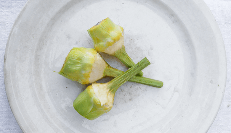 3 carciofi violetto puliti su piatto bianco