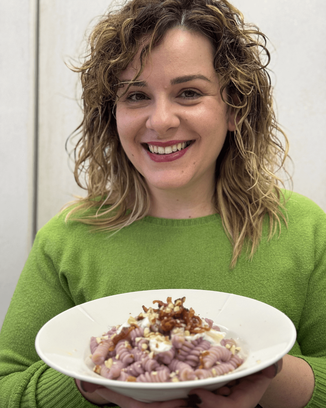 Ragazza con maglia verde che tiene in mano pasta viola